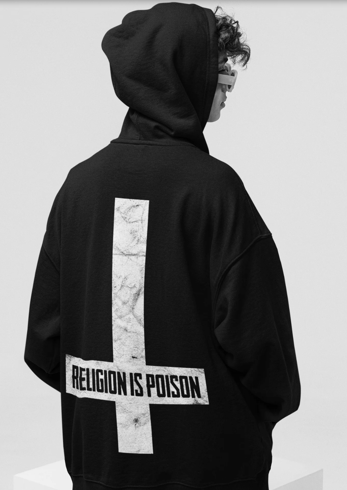 Person mit schwarzem Hoodie und Aufdruck „Religion is poison“ auf dem Rücken.